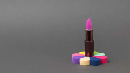 Bright stylish lipstick on a colorful stand on a dark gray background. Care for the female face.の写真素材