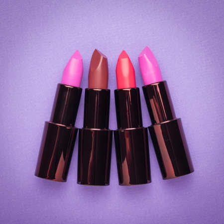 Four stylish lipsticks on a purple background. Lip decoration. Flat lay.の写真素材