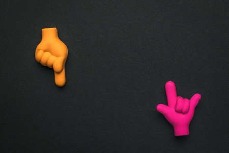 Two rubber hands showing gestures on a black background. Rubber figures of folded fingers.