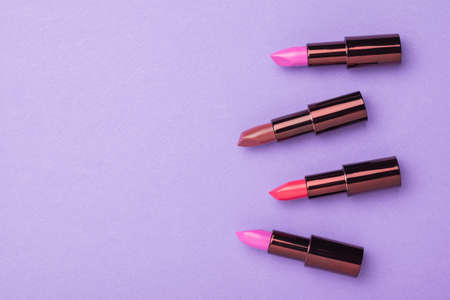 A banner with four tubes of lipstick on a purple background. Space for the text. Lip decoration....