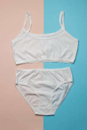 A set of white women's underwear on a two-tone background. Classic underwear for girls. Flat lay.