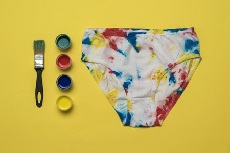 Paint and painted women's panties in the style of tie dye on a yellow background. Colored underwear at home.の写真素材