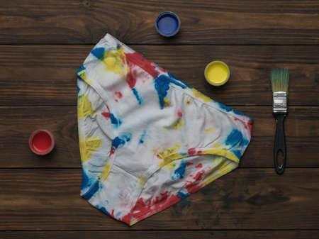 Women's panties in the style of tie dye and paint on a dark wooden background. Colored underwear at home.の写真素材