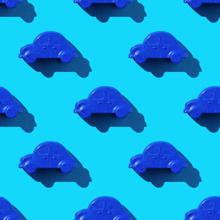 Seamless pattern of blue car toys on a blue background in bright light. The concept of selling and buying cars.の写真素材