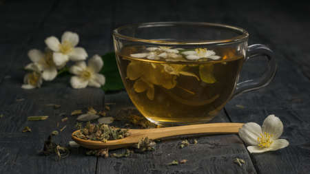 A wooden spoon with green tea and a cup of jasmine tea. An invigorating drink that is good for your health.の写真素材