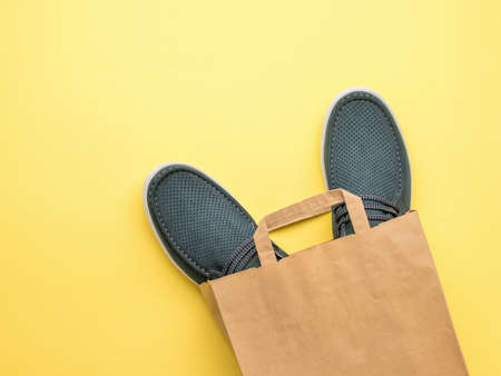 Men's summer shoes in a paper bag on a yellow background. Buying shoes. Flat lay.の写真素材