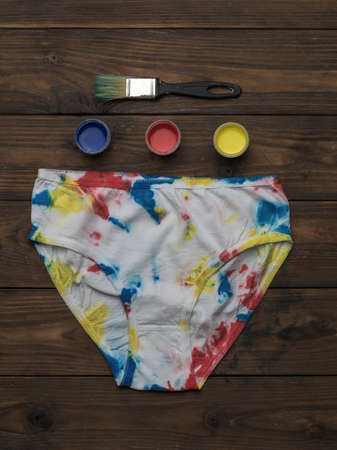 White underpants and fabric paints on a wooden background. Staining fabric in tie dye style.の写真素材