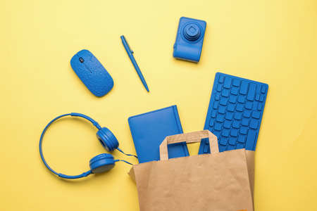 Paper bag with office accessories on a yellow background. Purchase items for the office. Flat lay.の写真素材