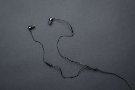 Black wired headphones for your phone on a black background. Equipment for listening to sound...