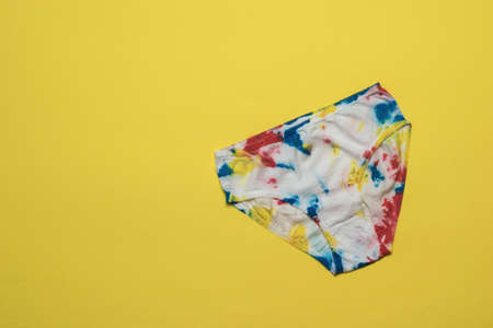 Women's panties are hand-painted in the style of tie dye on a bright yellow background. Colored...