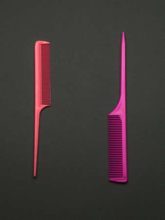 Two red hair combs on a dark background. A tool for hair care. Flat lay.