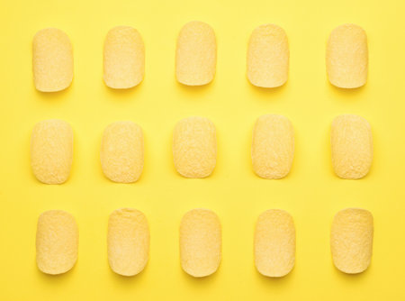 Neatly stacked potato chips on a yellow background. A popular potato dish. Flat lay.の写真素材