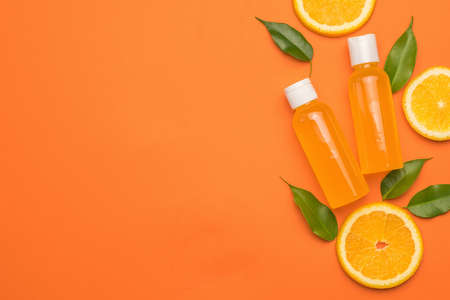 Leaves, orange slices and bottles of orange juice on an orange background. Space for the text. The concept of therapy with natural remedies. Flat lay.の写真素材