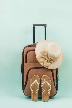 A travel suitcase, a woman's hat and women's sandals on a blue background. The concept of summer travel.の写真素材