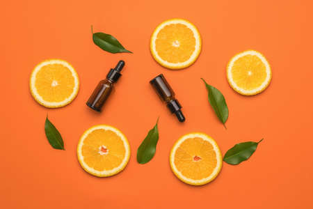Orange background with orange slices, green leaves and bottles with pipettes. The concept of therapy with natural remedies.の写真素材