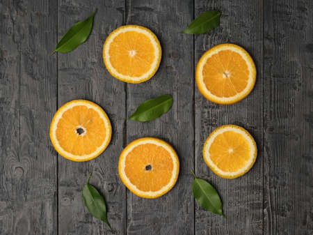 Five pieces of orange and green leaves on a wooden background. A popular tropical fruit. Flat lay.