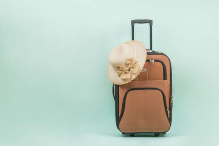 A woman's hat and a travel suitcase with a handle on a blue background. Space for the text. The concept of summer travel.の写真素材