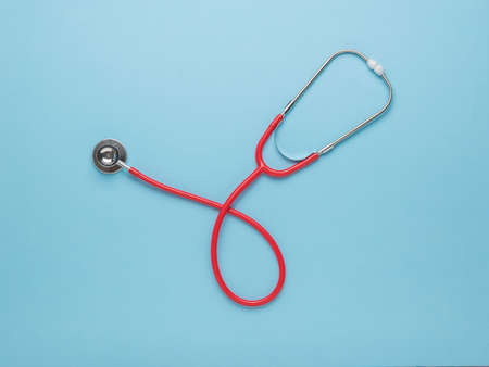 Classic red stethoscope on a blue background. The concept of treatment of various diseases. Flat lay.の写真素材