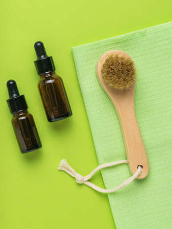 Two bottles with pipettes and a facial massager on a green background. The concept of body care. Spa. Flat lay.の写真素材