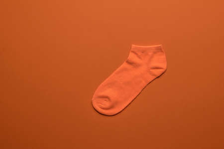 Bright orange sock on an orange background. A stylish sports accessory. Flat lay.の写真素材