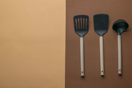 Three kitchen spatulas on a two-color background. Space for the text. Plastic kitchen tools. Flat...
