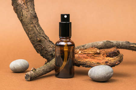 Spray bottle, old wood and stones on a brown background. Cosmetics and medicinal products based on natural minerals. The concept of treatment and body care using natural remedies.の写真素材