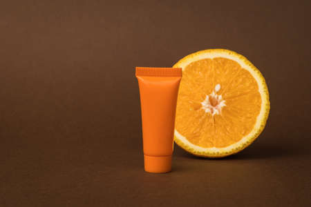 An orange tube with cream and an orange on a brown background. Cosmetics and therapeutic ointments based on natural minerals.の写真素材