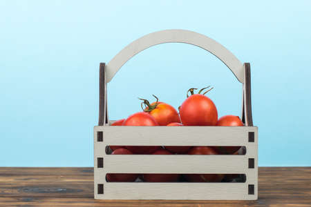 Red ripe tomatoes in a box on a wooden table. A fresh crop of vegetables.の写真素材