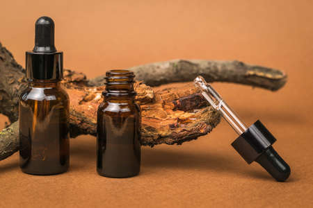 Closed and open dropper bottle on a brown background. Cosmetics and medicinal products based on natural minerals. The concept of treatment and body care using natural remedies.の写真素材