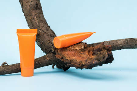 An old dry tree and two tubes of cream on a blue background. Cosmetics and therapeutic ointments based on natural minerals.の写真素材