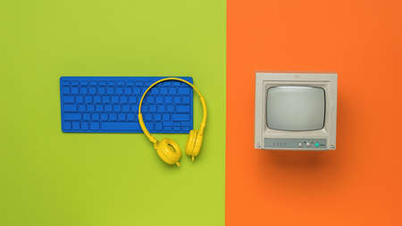 Vintage monitor and blue keyboard on an orange background. Retro equipment. Flat lay.の写真素材
