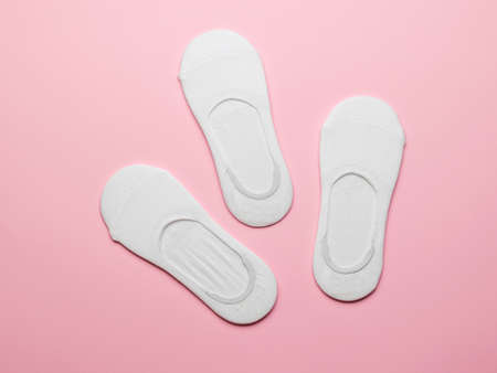 Three pairs of packed women's white short socks on a pink background. A stylish sports accessory. Flat lay.の写真素材