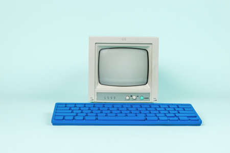 An antique monitor and a stylish blue keyboard on a light blue background. Vintage equipment.の写真素材