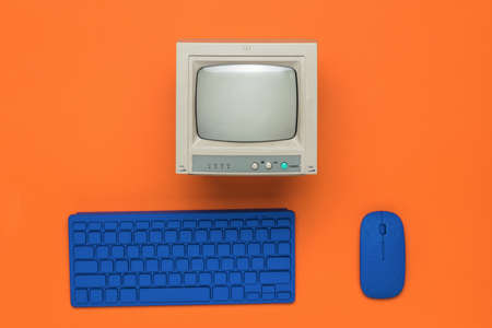 A gray monitor and a blue keyboard and mouse on an orange background. Vintage equipment.の写真素材