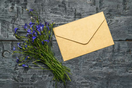 A bouquet of flowers and a postal paper envelope on a wooden table. The concept of love correspondence. Flat lay.の写真素材