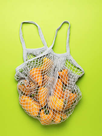 Fresh bell pepper in a mesh bag on a green background. Vegetarian food. A fresh crop of vegetables.