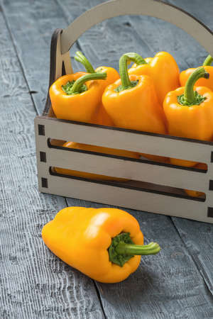 Bright Bulgarian pepper in a wooden box on a wooden table. Vegetarian food. A fresh crop of vegetables.の写真素材