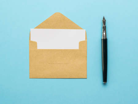 A fountain pen and an open postal envelope with a white sheet on a blue background. The concept of mail correspondence. Flat lay.の写真素材