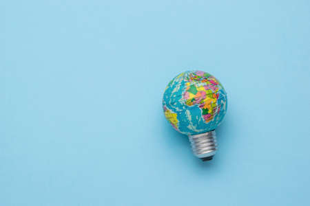 A globe-shaped light bulb on a light blue background. The concept of switching to green energy.の写真素材