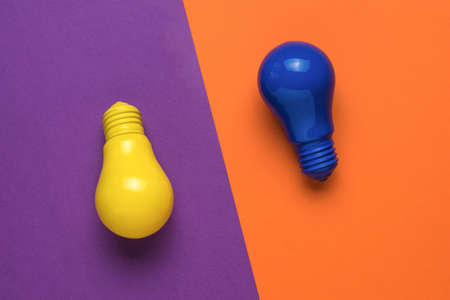 Yellow and blue light bulbs on a yellow and orange background. Minimalism. The concept of energy and business. Flat lay.の写真素材