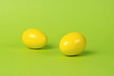 Two bright yellow eggs on a green background. Creative photo of eggs.の写真素材