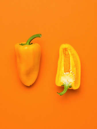 Ripe whole orange bell pepper and half on an orange background. Vegetarian food. A fresh crop of vegetables.の写真素材