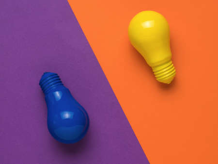 Blue and yellow light bulbs on an orange and purple background. Minimalism. The concept of energy and business. Flat lay.の写真素材