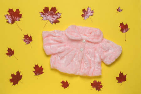 A warm women's cape and red maple leaves on a yellow background. The concept of autumn cold weather. Flat lay.の写真素材