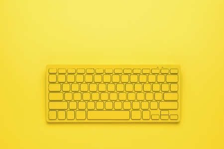 Yellow wireless keyboard on a bright yellow background. Monochrome image of office accessories.の写真素材