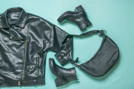 A set of leather jacket, bag and boots on a blue background. Stylish women's set. Flat lay.の写真素材