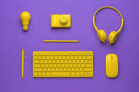 A set of yellow workplace accessories on a purple background. The concept of business and...