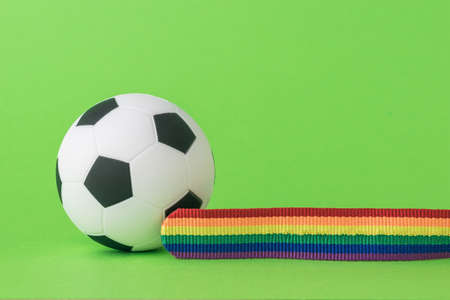 Soccer ball and LGBT tape on a green background. The concept of LGBT in football. Space for text.の写真素材