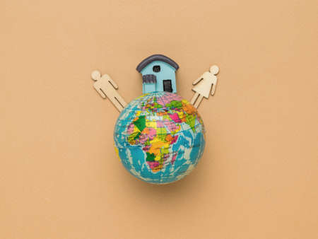 A globe, a house and two figures of a man and a woman on a brown background. The concept of family, planet, earth, happiness.の写真素材