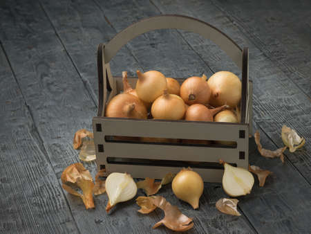 Freshly picked onions in a wooden box and on a wooden table. Autumn harvest.の写真素材